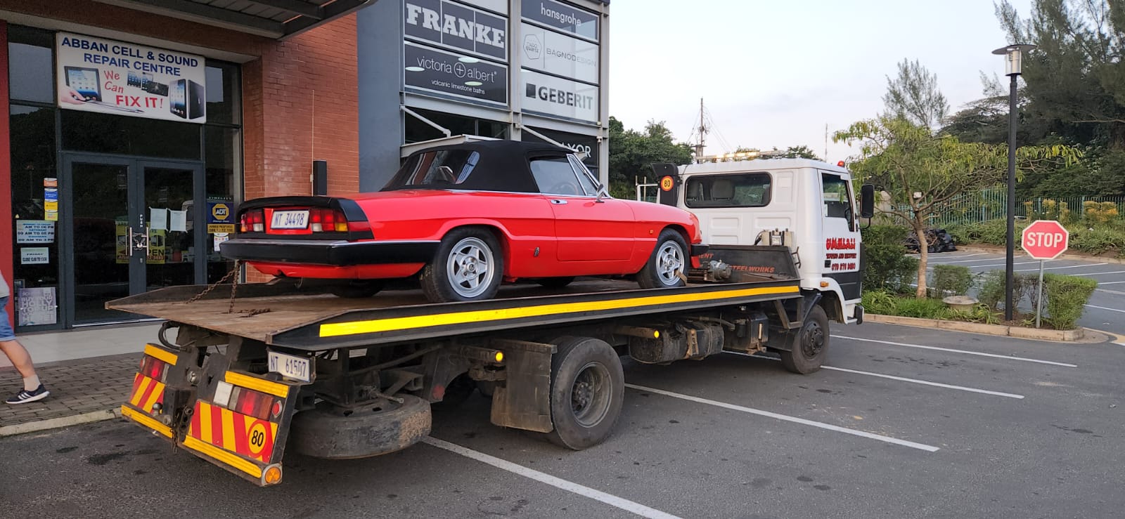 Red classic Alfa Romeo Spider convertible on a flatbed