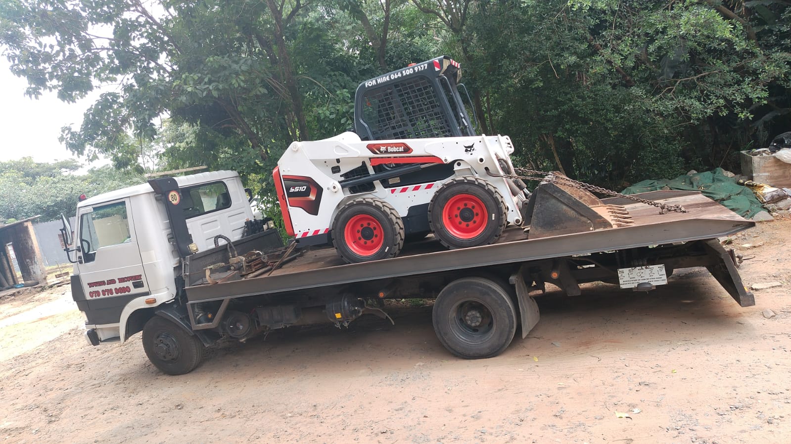 Bobcat S510 skid-steer loaded on a flatbed tow truck