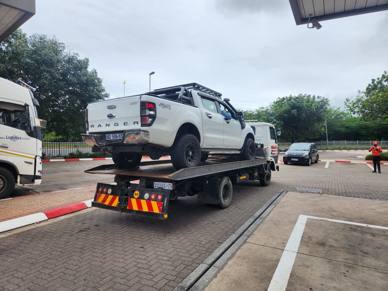 White Ford Ranger 4x4 loaded on an Umhlali flatbed tow truck at a fuel station